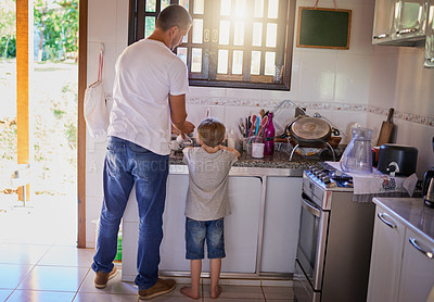 Buy stock photo Father, child and cleaning dishes in kitchen for helping hand, teaching hygiene or bonding. Back, man and boy kid with housekeeping in home for learning responsibility, chores support and development