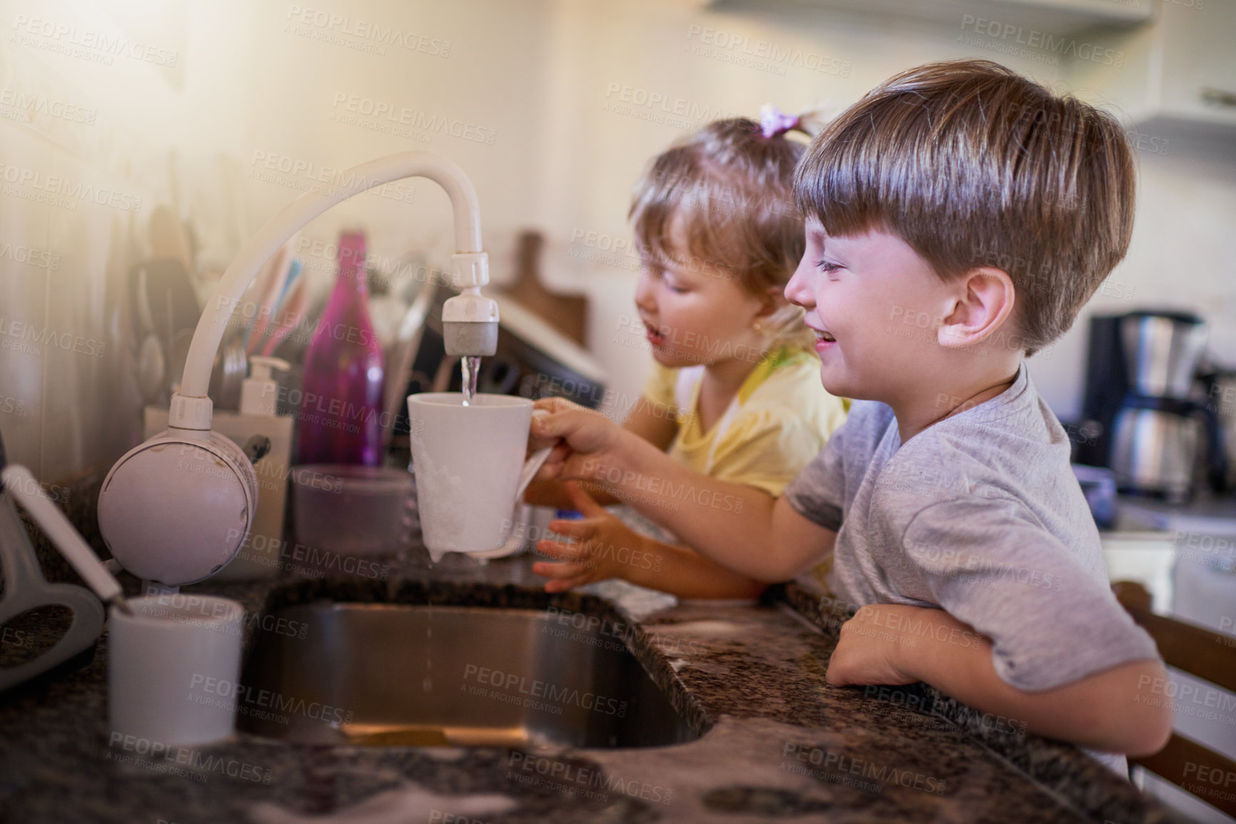 Buy stock photo Shot of two adorable little siblings washing dishes together in the kitchen at home