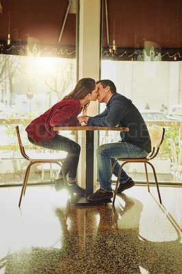 Buy stock photo Couple, kiss and holding hands with love at cafe for valentines day, romantic celebration and commitment. Happy, people and support with relationship date, loyalty and bonding together at restaurant