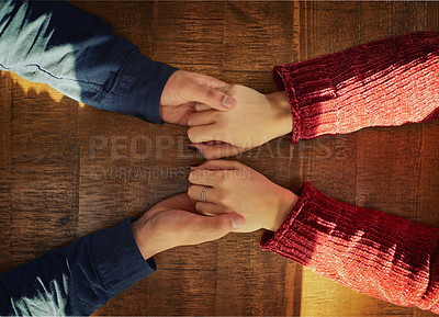 Buy stock photo Cropped high angle shot of an unidentifiable man and woman holding hands on a table