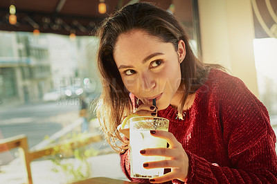 Buy stock photo Shot of a young woman enjoying a fresh beverage in a coffee shop