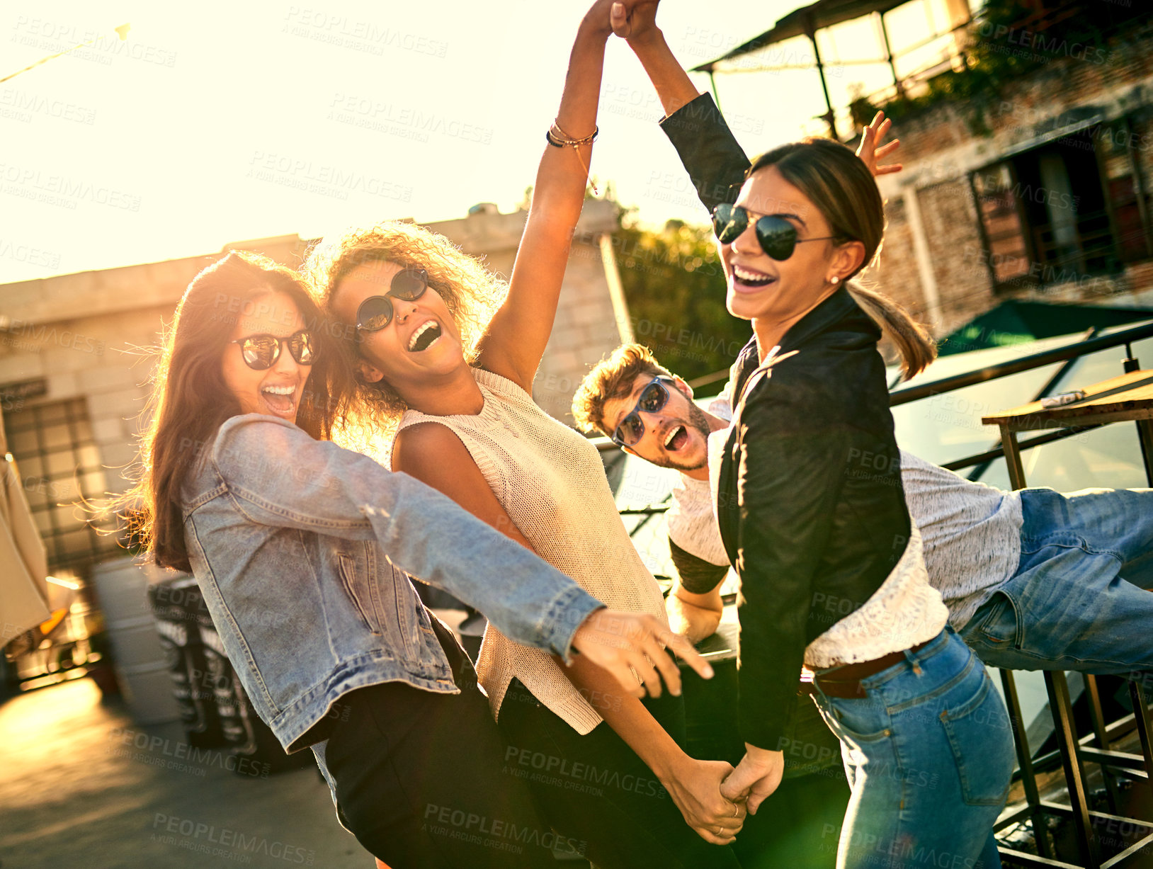 Buy stock photo Cropped shot of a group of young friends spending the day outside on a rooftop