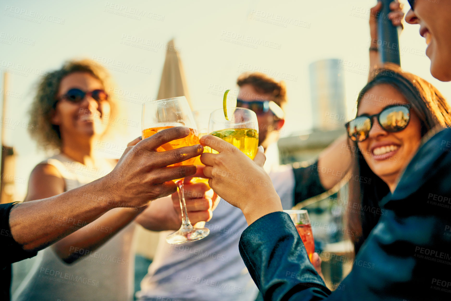 Buy stock photo Cropped shot of a group of young diverse friends having a drink and spending the day outside on a rooftop