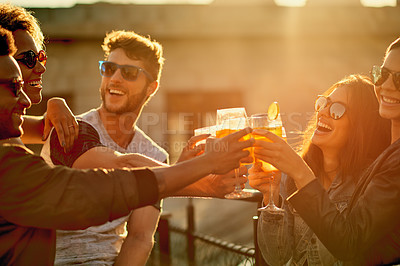 Buy stock photo Cropped shot of a group of young diverse friends having a drink and spending the day outside on a rooftop
