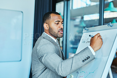 Buy stock photo Shot of a young businessman writing on a whiteboard in an office