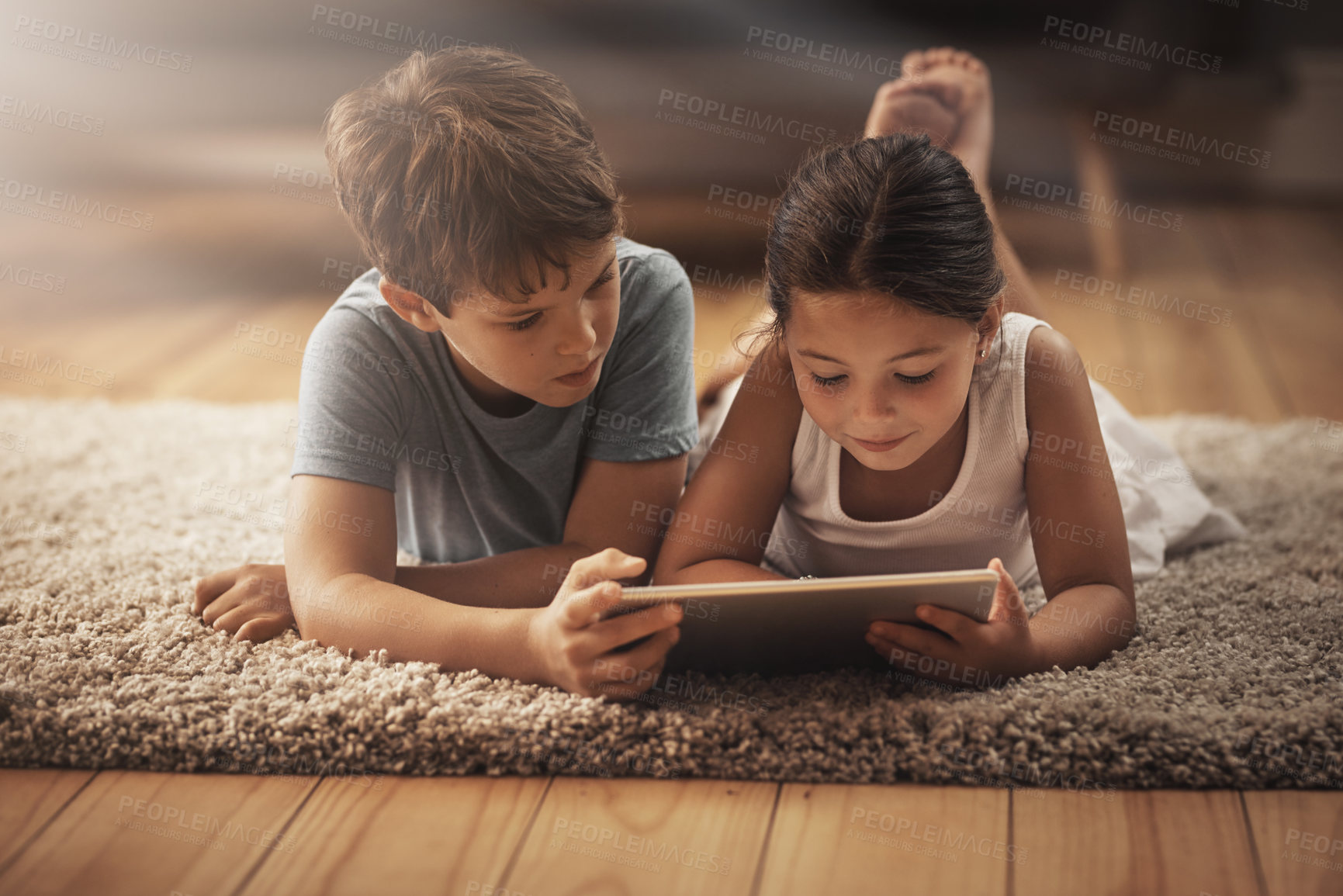 Buy stock photo Shot of an adorable brother and sister using a digital tablet together on the floor at home