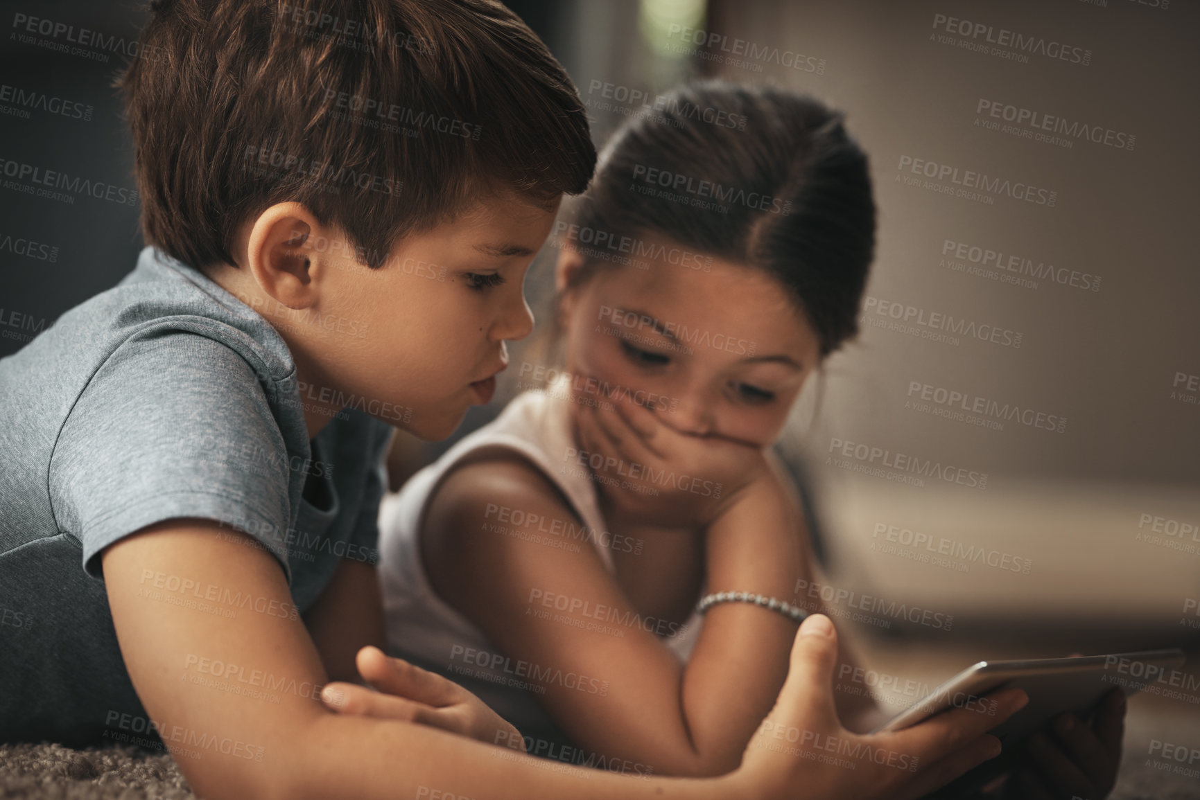 Buy stock photo Shot of an adorable brother and sister using a digital tablet together on the floor at home