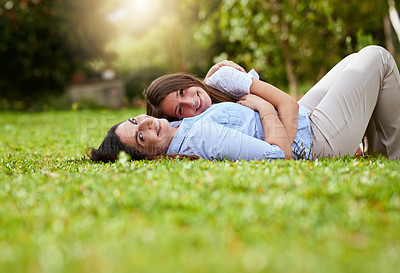 Buy stock photo Portrait of a cheerful mother and her young daughter lying on grass inside a park outside during the day