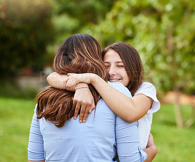 Buy stock photo Shot of a cheerful young mother and daughter giving each other a hug while standing outside in a park during the day