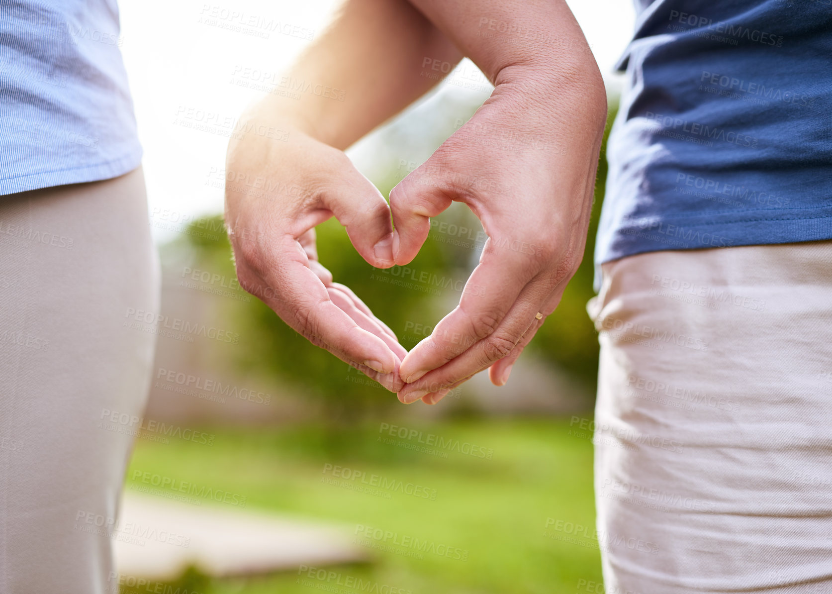 Buy stock photo Closeup of two unrecognizable people forming a heart together with their hands while standing outside in a park during the day