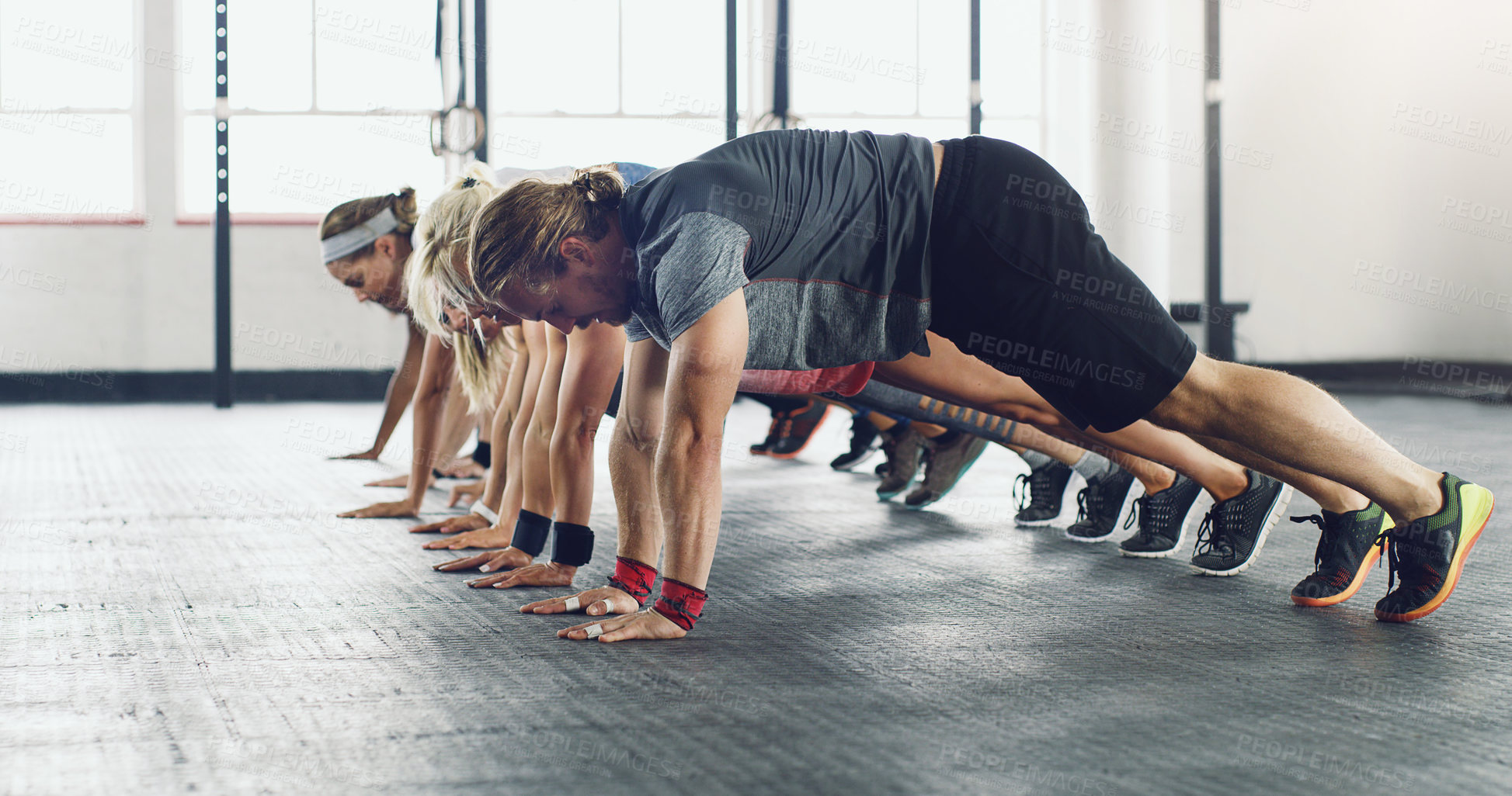 Buy stock photo Shot of a group of young people doing push ups in a gym