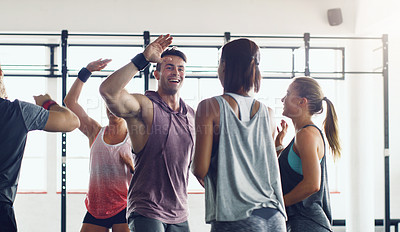 Buy stock photo Shot of a group of young people motivating each other with a high five in a gym