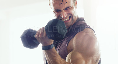 Buy stock photo Shot of a muscular young man lifting weights in a gym