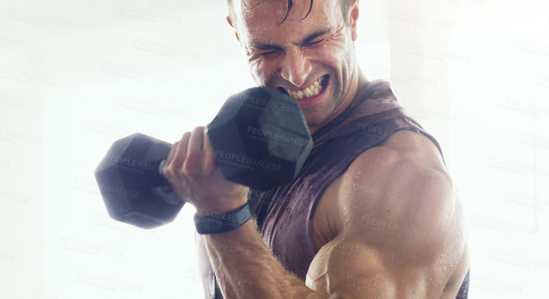 Buy stock photo Shot of a muscular young man lifting weights in a gym