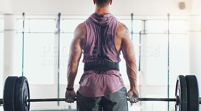 Buy stock photo Rearview shot of a muscular man lifting a barbell in a gym