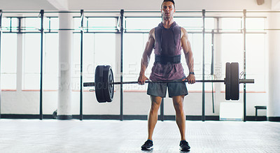 Buy stock photo Shot of a muscular young man lifting a barbell in a gym