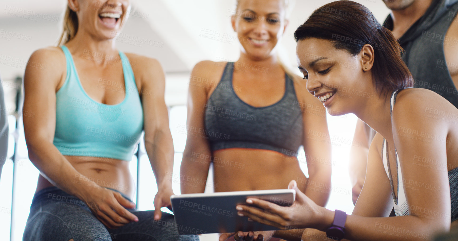 Buy stock photo Shot of a group of happy young women using a digital tablet together in a gym