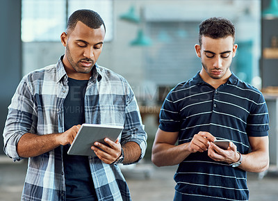 Buy stock photo Shot of two young designers using digital devices in an office