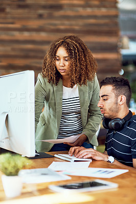 Buy stock photo Shot of two young designers working together on a computer in an office