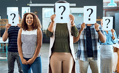 Buy stock photo Portrait of a young businesswoman standing amongst her colleagues holding up placards with question marks on in an office