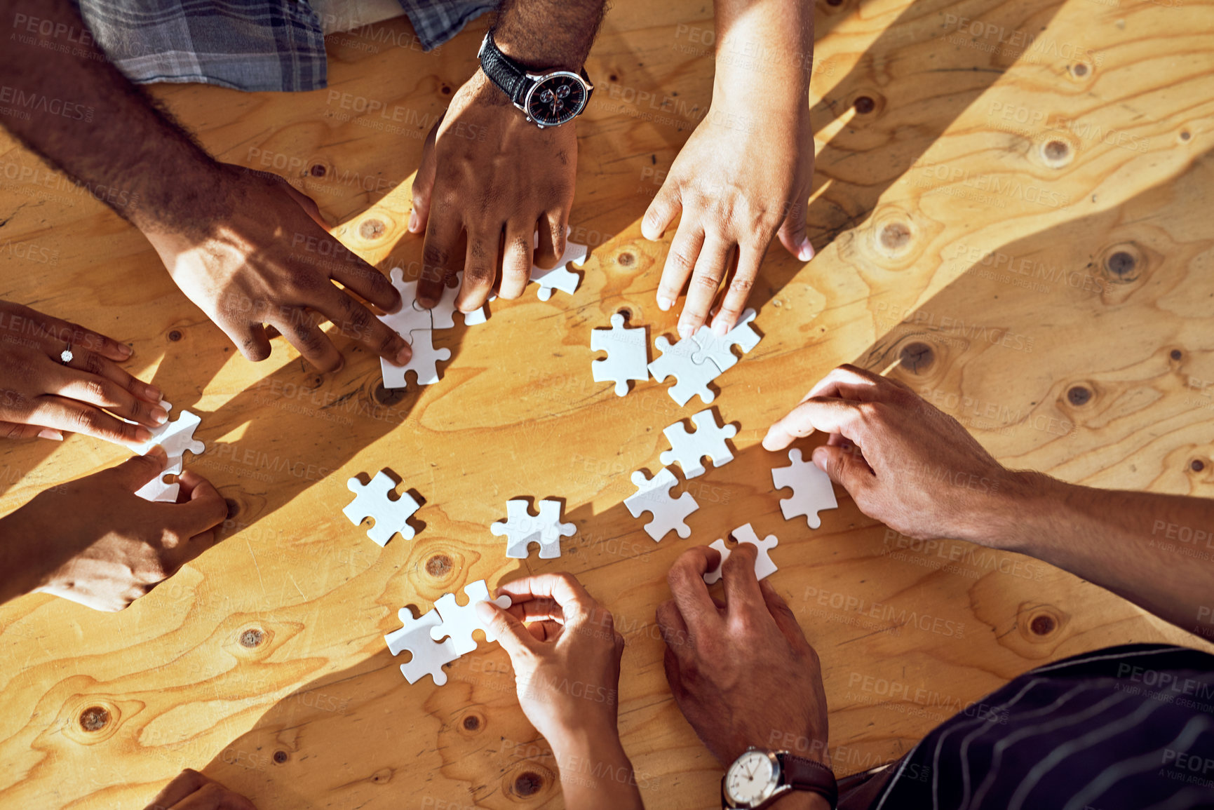 Buy stock photo Closeup shot of an unrecognizable group of people completing a puzzle together