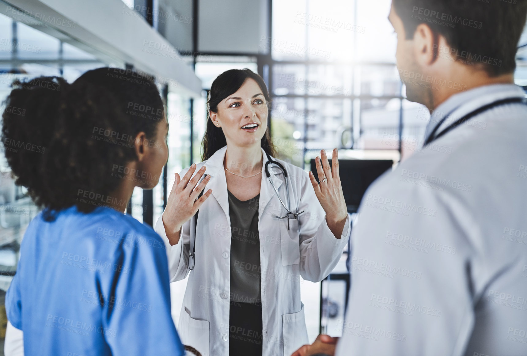 Buy stock photo Shot of a team of doctors having a discussion in a hospital