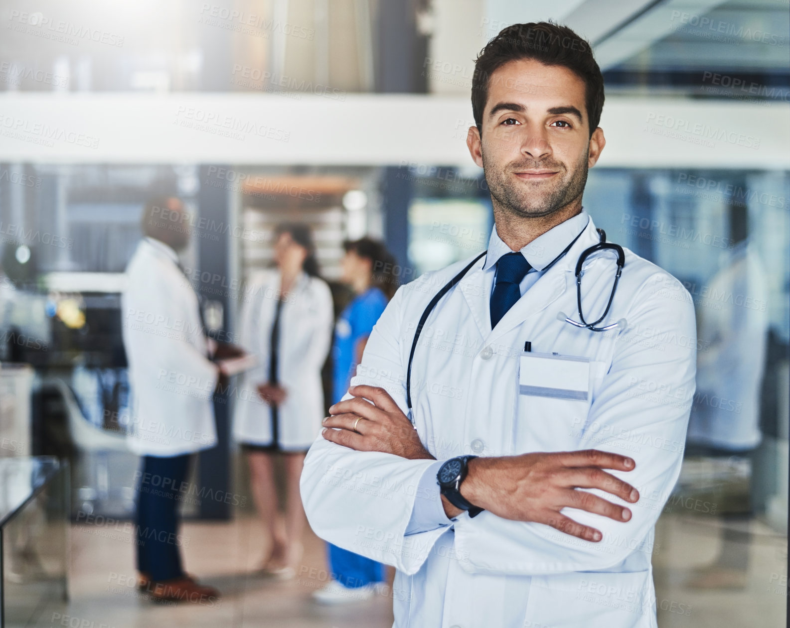 Buy stock photo Portrait of a confident doctor working in a hospital with his colleagues in the background
