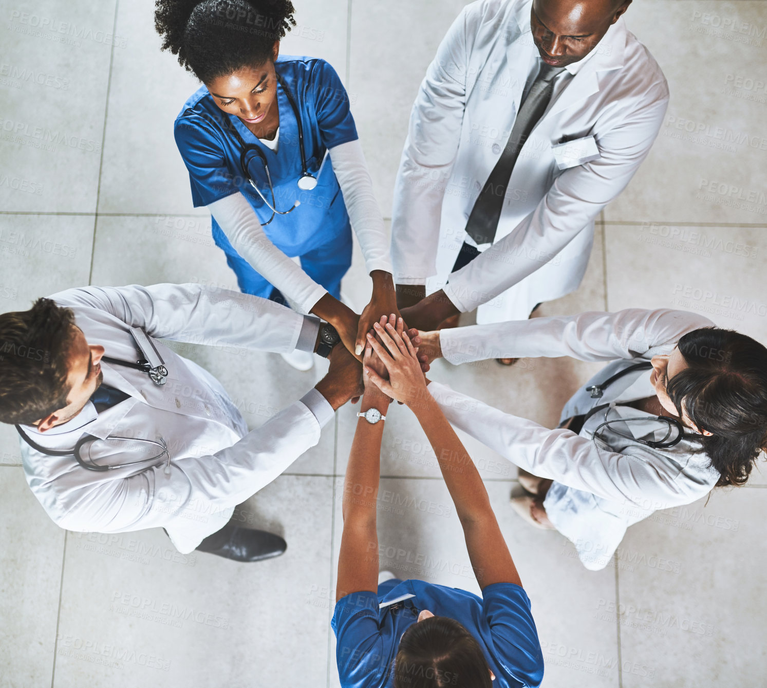 Buy stock photo High angle shot of a diverse team of doctors joining their hands together in a hospital