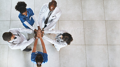 Buy stock photo High angle shot of a diverse team of doctors joining their hands together in a hospital