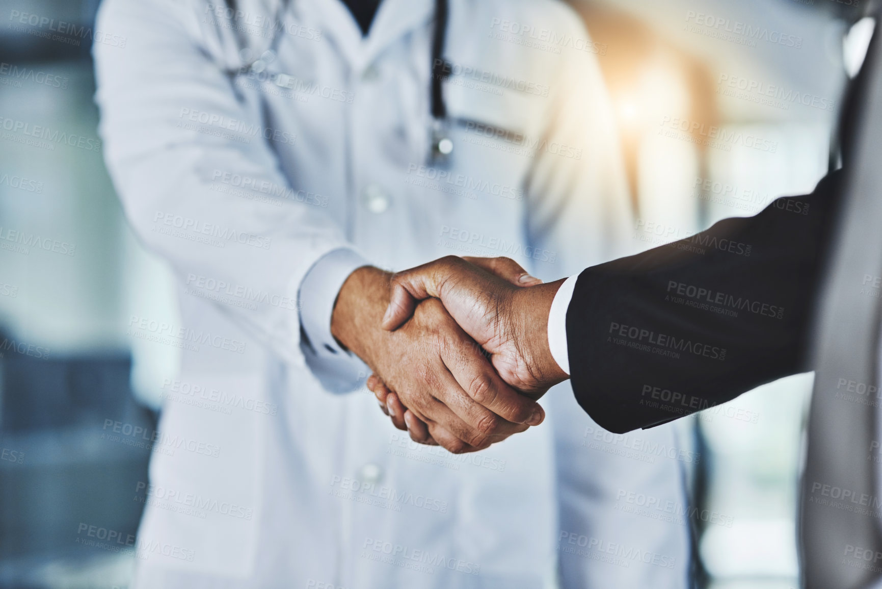 Buy stock photo Cropped shot of a doctor shaking hands with a businessman in a hospital