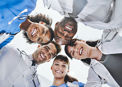 Buy stock photo Low angle portrait of a diverse team of doctors huddled together in a hospital