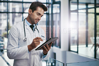 Buy stock photo Cropped shot of a young handsome male medical practitioner working in a hospital