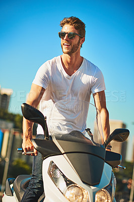 Buy stock photo Shot of a young man riding a motorbike through the city