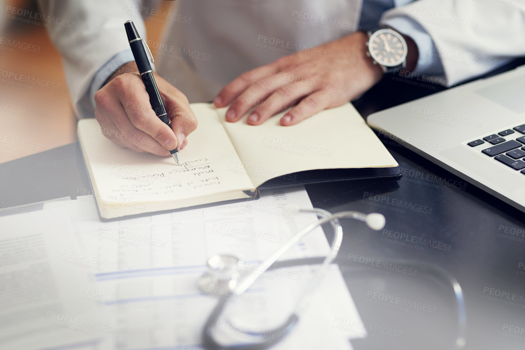 Buy stock photo High angle shot of an unrecognizable male doctor writing in his diary while sitting in his office