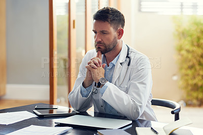 Buy stock photo Cropped shot of a handsome male doctor looking thoughtful while sitting in his office