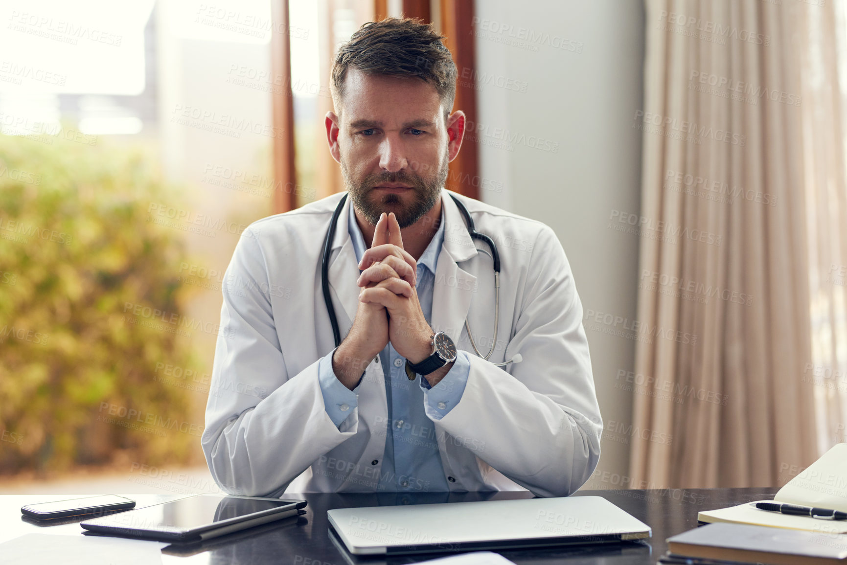Buy stock photo Cropped shot of a handsome male doctor looking thoughtful while sitting in his office