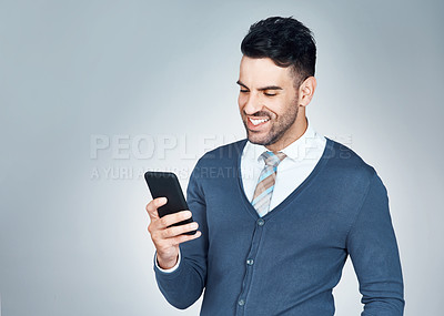 Buy stock photo Studio shot of a handsome young businessman using a cellphone against a grey background