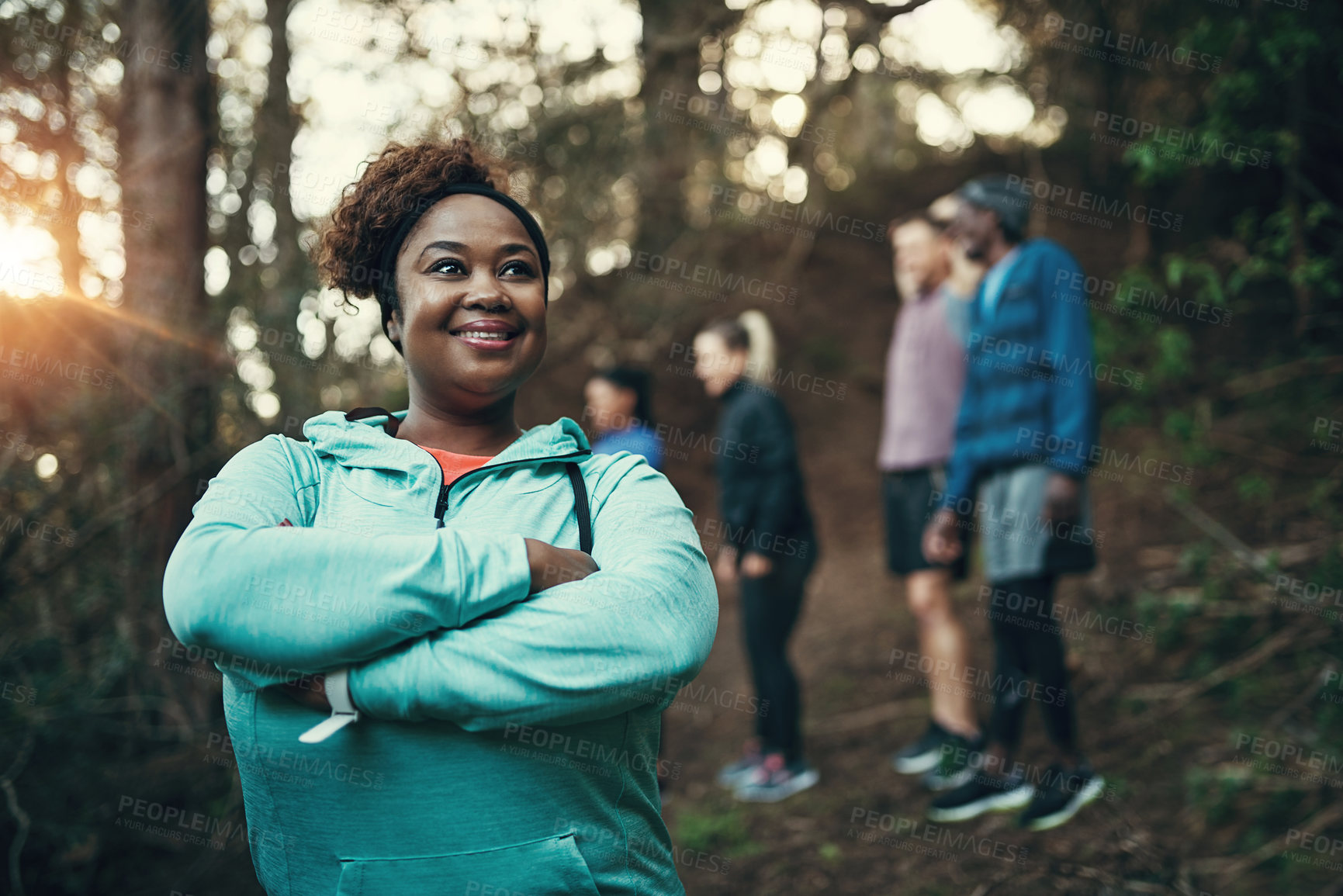 Buy stock photo Cropped shot of a sporty young woman ready to workout while waiting for her friends in the background in the forest