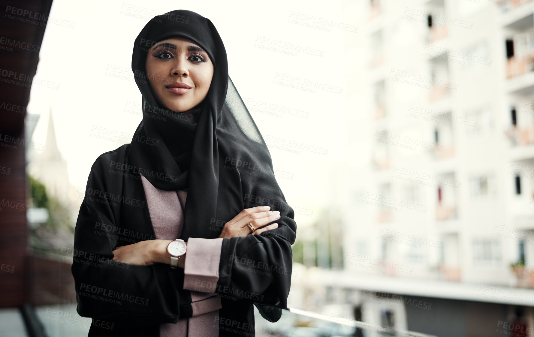 Buy stock photo Cropped portrait of an attractive young businesswoman dressed in Islamic traditional clothing standing with her arms crossed on her office balcony