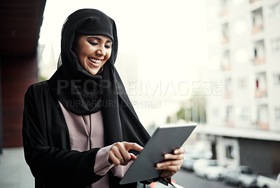 Buy stock photo Cropped shot of an attractive young businesswoman dressed in Islamic traditional clothing using a tablet while standing on her office balcony