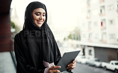 Buy stock photo Cropped shot of an attractive young businesswoman dressed in Islamic traditional clothing using a tablet while standing on her office balcony