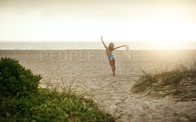 Buy stock photo Rearview shot of a happy young woman enjoying a day at the beach