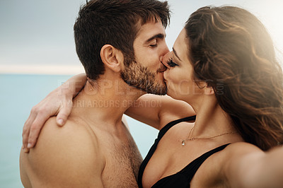 Buy stock photo Shot of a young couple kissing on the beach