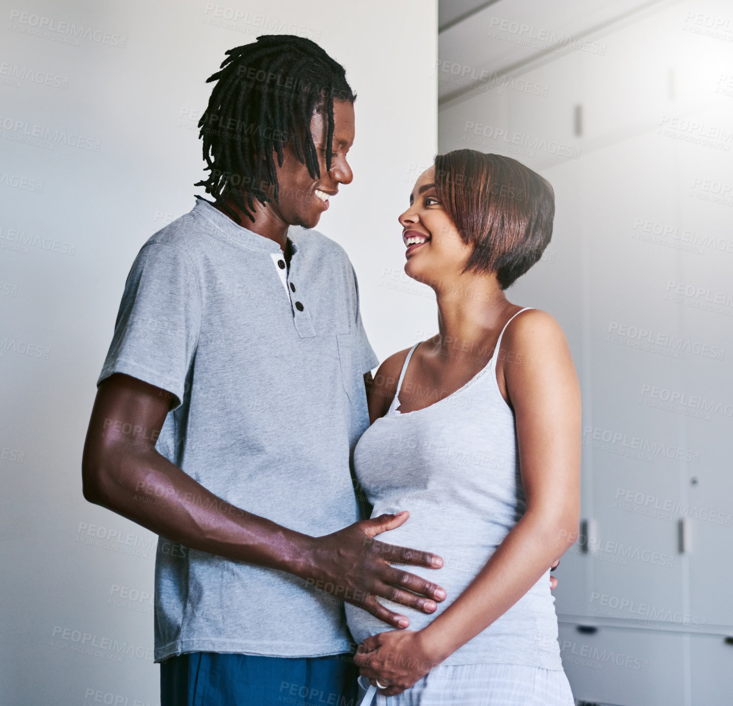 Buy stock photo Shot of a young man touching his pregnant wife's belly