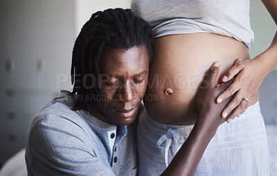 Buy stock photo Cropped shot of a man listening to his wife's pregnant belly