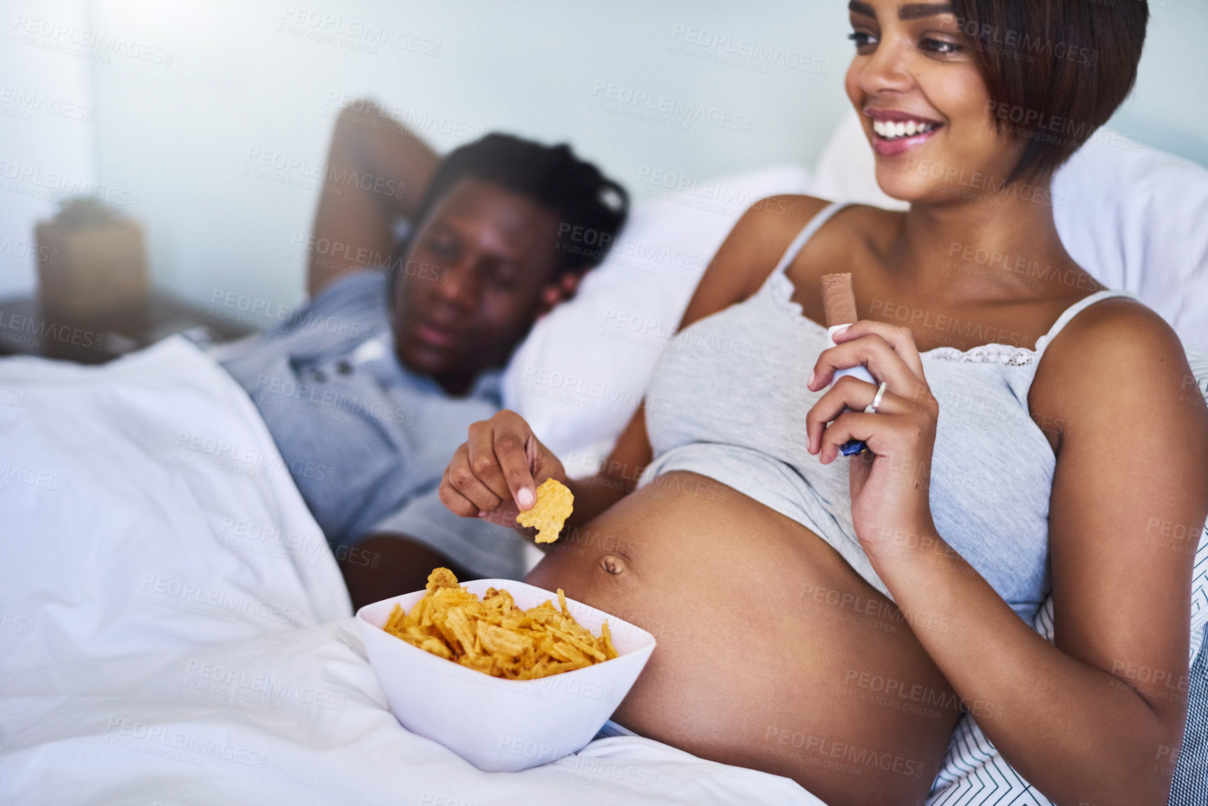 Buy stock photo Cropped shot of a pregnant woman enjoying a chocolate and potato chips in bed