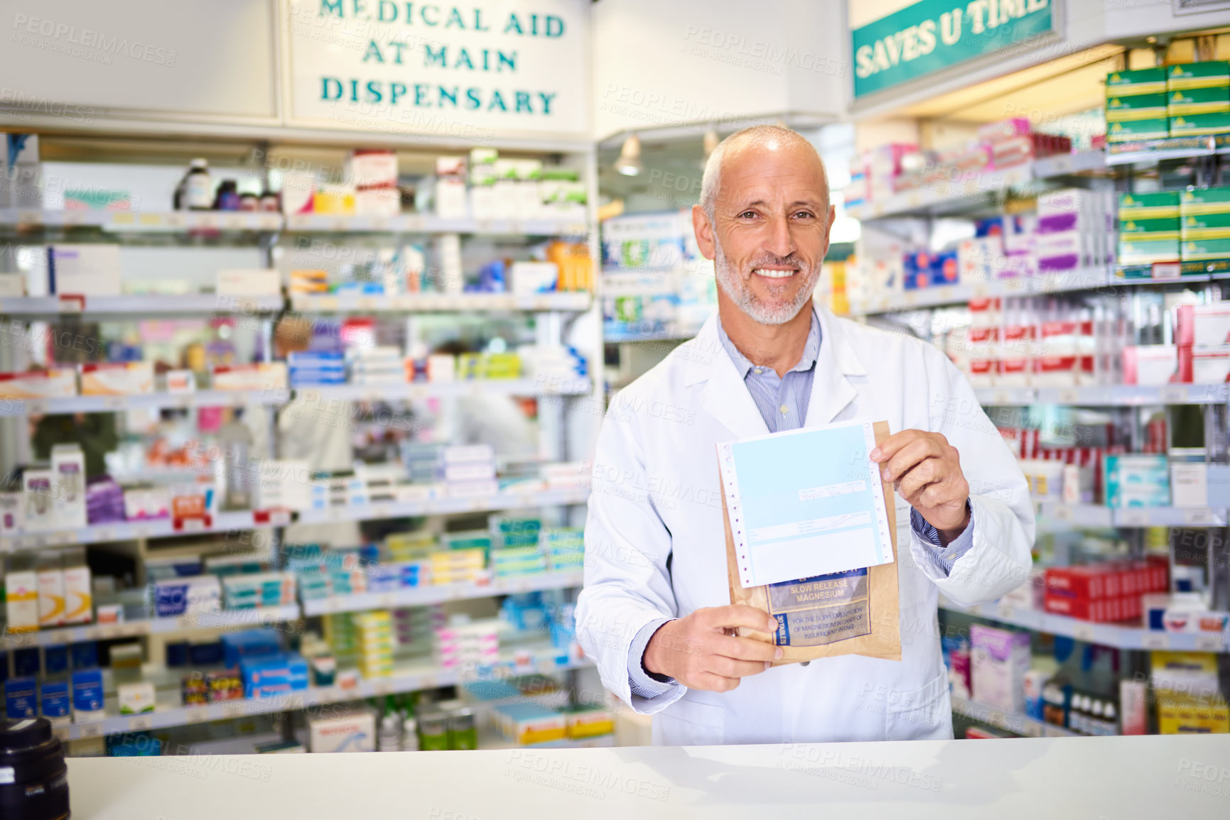 Buy stock photo Portrait of a mature pharmacist holding a paper bag with medication in a chemist