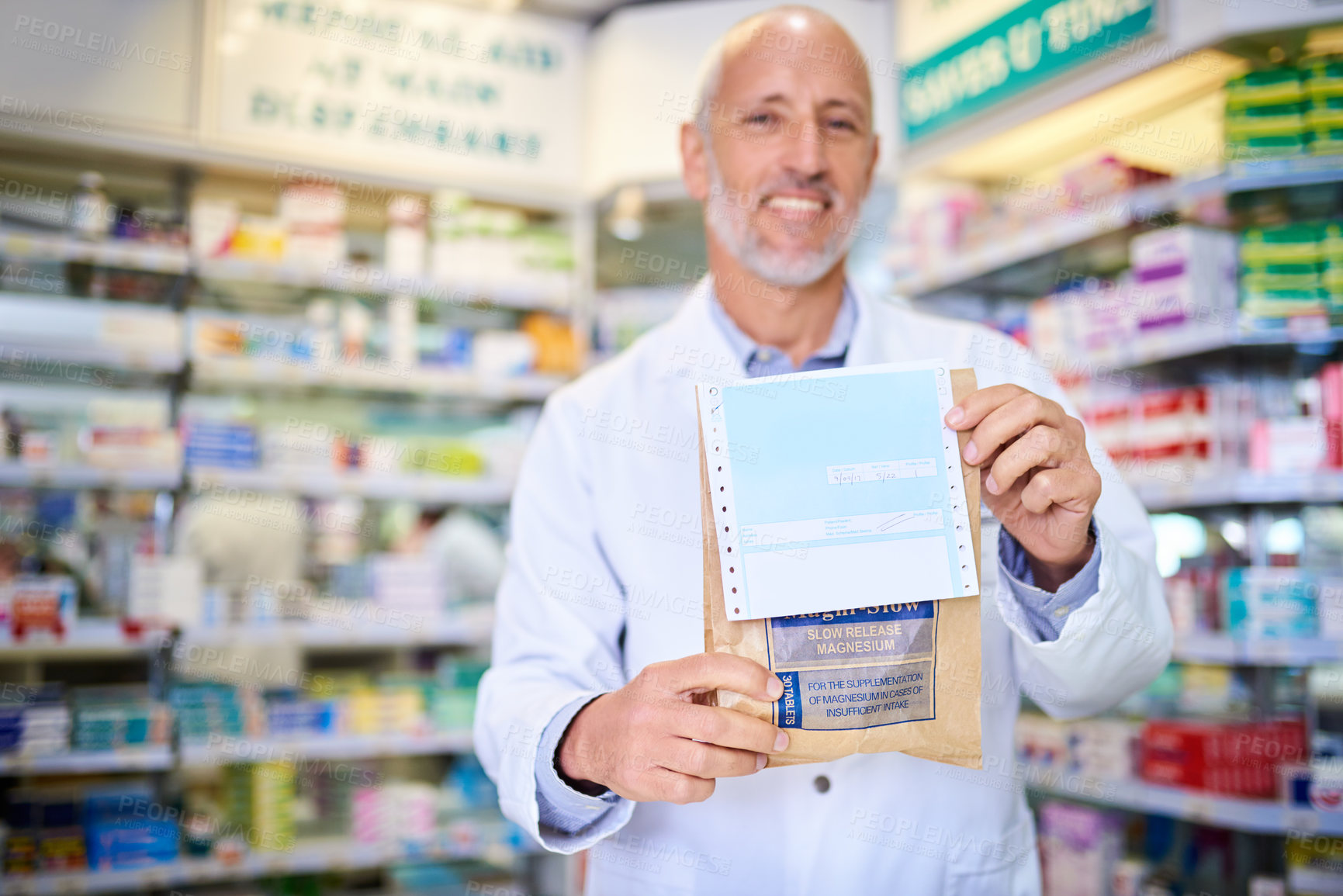 Buy stock photo Portrait of a mature pharmacist holding a paper bag with medication in a chemist