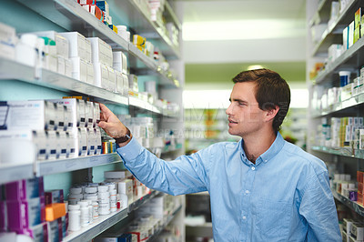 Buy stock photo Cropped shot of a handsome young man looking for medication in a pharmacy