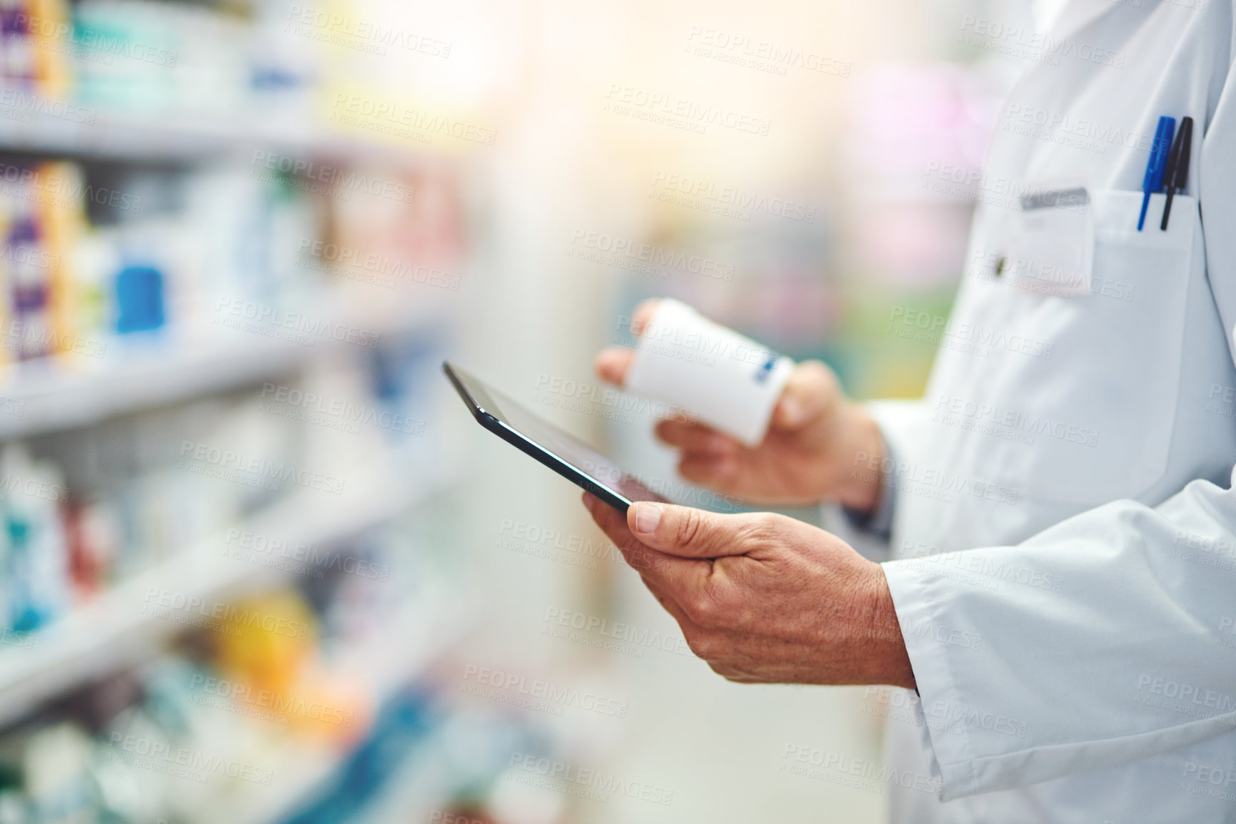 Buy stock photo Cropped shot of an unrecognizable male pharmacist using a tablet while working in the pharmacy